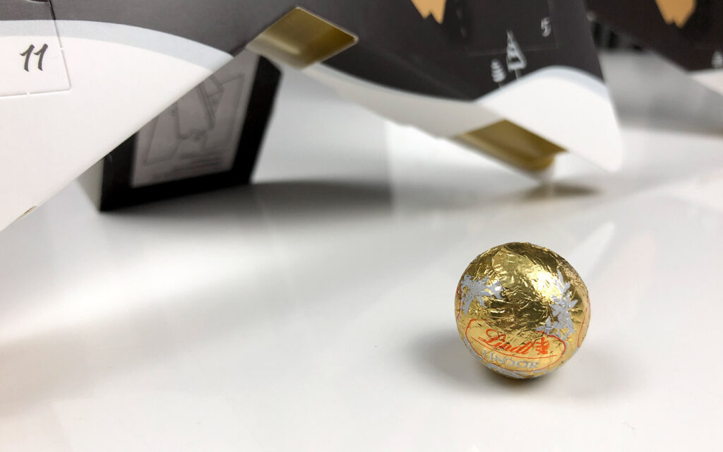 Eine der Füllungen des Adventskalenders Stern liegt vor dem Kalender selbst.