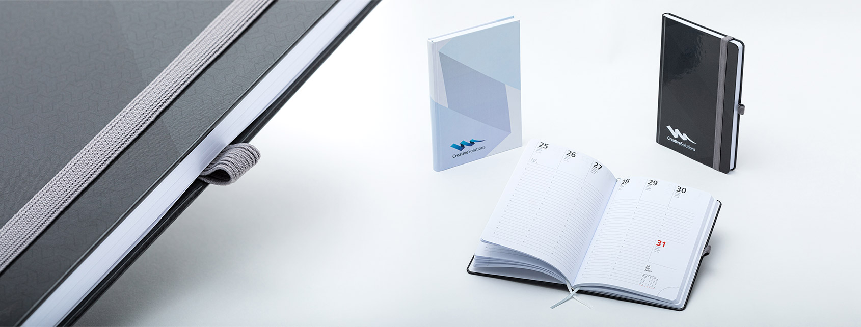 Verschiedene Notizbücher mit Hardcover, aufgeschlagen oder geschlossen stehend.
