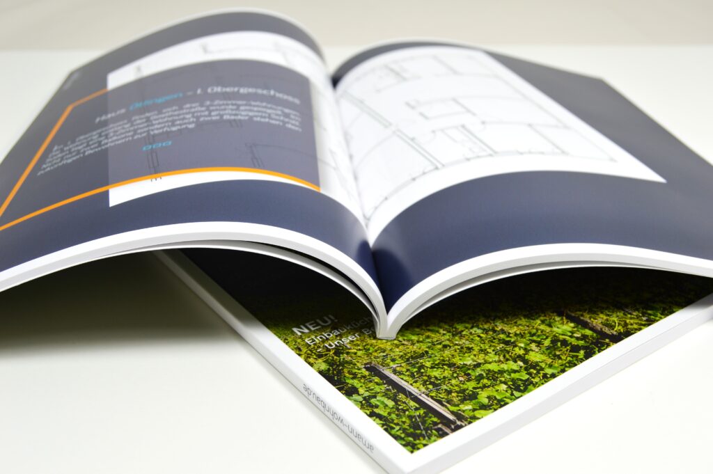 Aufgeschlagene Broschüre liegt auf geschlossener Broschüre