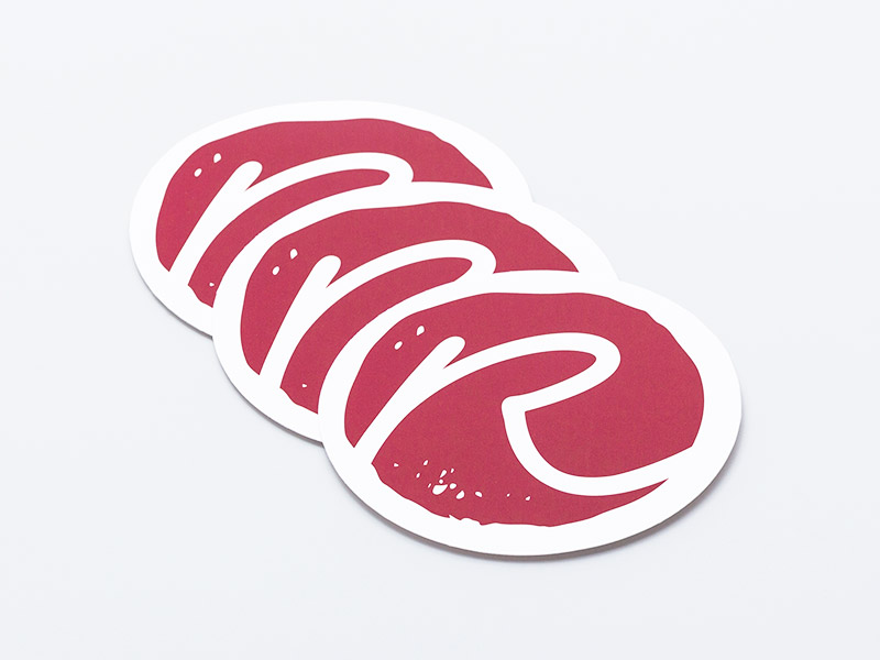 Auf dem Bild sind drei runde Aufkleber mit rotem Aufdruck zu sehen.