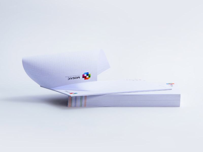 Die Abbildung zeigt die Längsseite eines Stapels mit Blöcken. Der obere Block liegt leicht versetzt auf und das obere Blatt wurde geschwungen wie beim Aufblättern dargestellt.