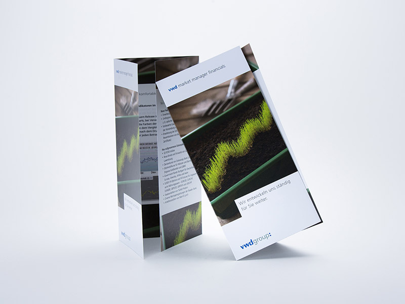 Die Abbildung zeigt zwei aufrecht stehende und zum Teil aufgeklappt Flyer mit Wickelfalt im DIN lang Hochformat.