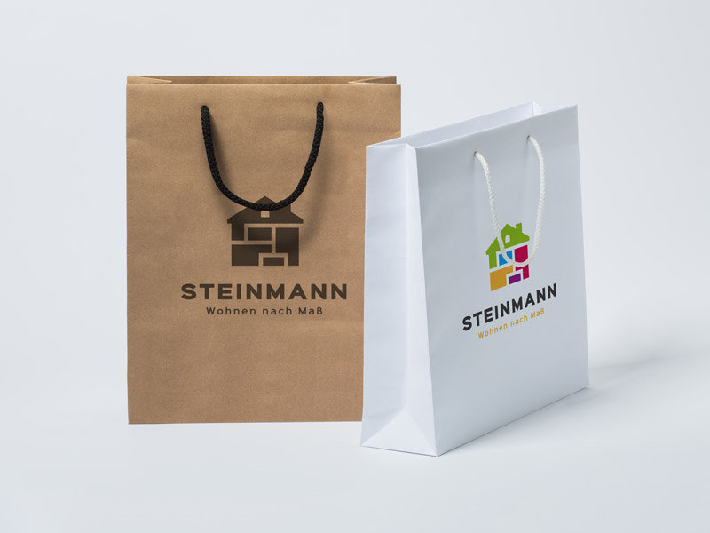 Die Abbildung zeigt eine braune Kraftpapiertasche, die frontal platziert ist und eine schwarze Kordel sowie einen schwarzen Aufdruck hat. Seitlich gestellt ist eine weiße Papiertasche zu sehen.weiße Papiertasche im Querformat aus einerseitlichen Ansicht. Sie hat eine weiße Stoffkordel und ein buntes Logo als Aufdruck.